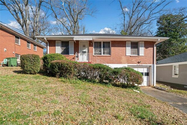 view of front of home with brick siding, an attached garage, driveway, and a front yard