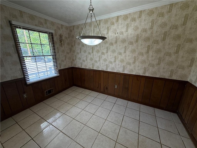 unfurnished dining area featuring visible vents, crown molding, wainscoting, light tile patterned floors, and wooden walls