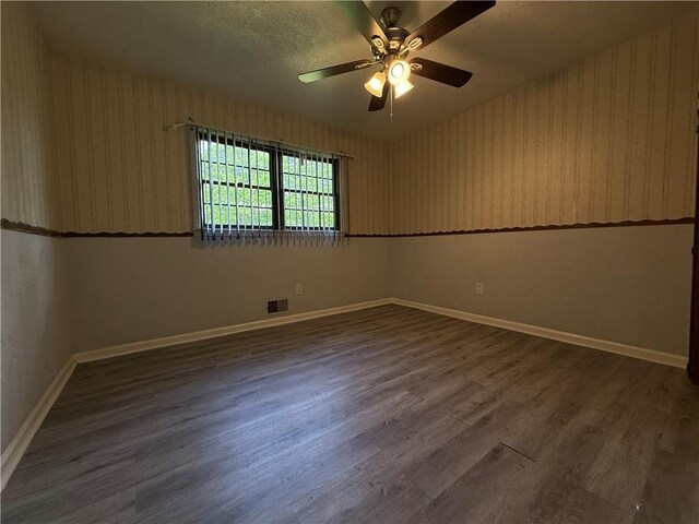 spare room with baseboards, ceiling fan, wood finished floors, and visible vents