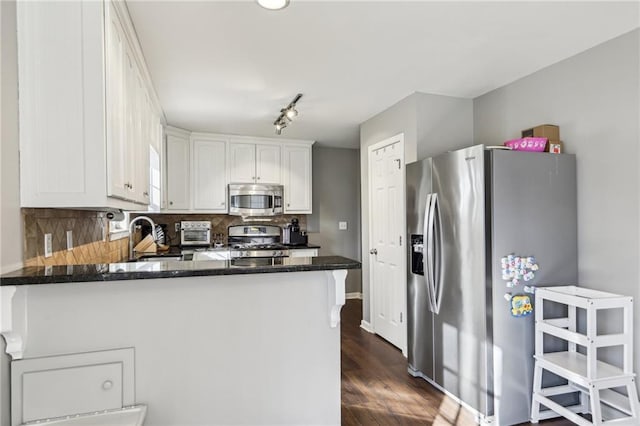 kitchen with white cabinets, stainless steel appliances, tasteful backsplash, sink, and kitchen peninsula