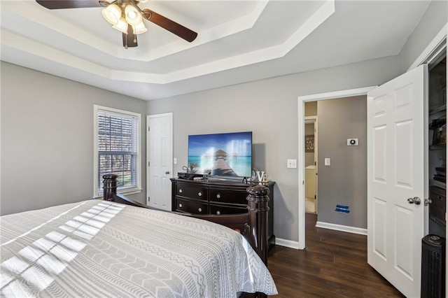 bedroom featuring a raised ceiling, ceiling fan, and dark wood-type flooring