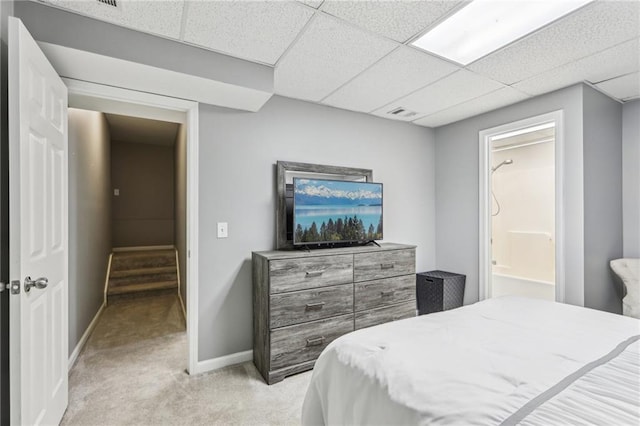 carpeted bedroom featuring connected bathroom and a drop ceiling