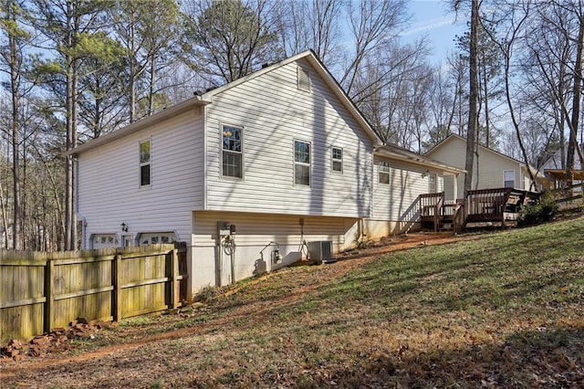 exterior space featuring central AC unit, a wooden deck, and a lawn