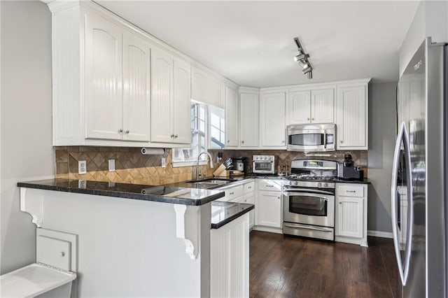 kitchen with white cabinetry, kitchen peninsula, appliances with stainless steel finishes, backsplash, and sink