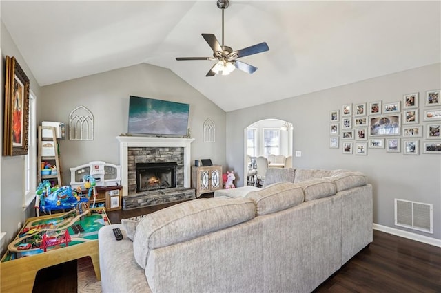 living room featuring ceiling fan, dark hardwood / wood-style flooring, a stone fireplace, and lofted ceiling