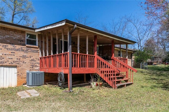 back of property featuring brick siding, central AC unit, stairs, and a yard