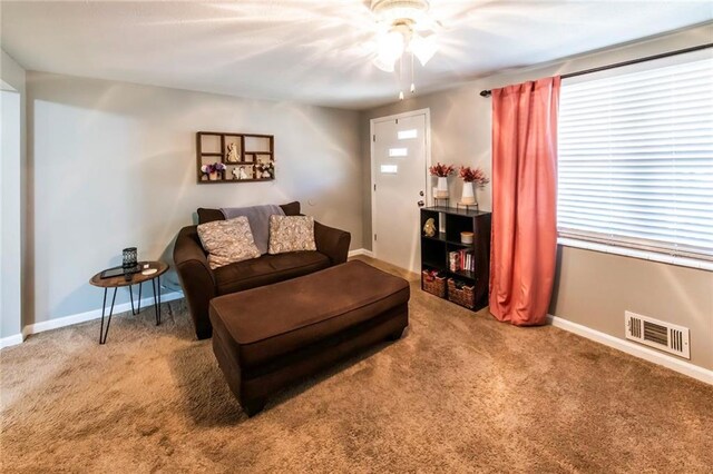 living area with baseboards, visible vents, carpet floors, and a ceiling fan
