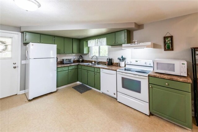 kitchen featuring green cabinets, under cabinet range hood, a sink, and white appliances