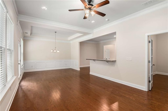 empty room featuring a raised ceiling, crown molding, dark hardwood / wood-style flooring, and ceiling fan with notable chandelier