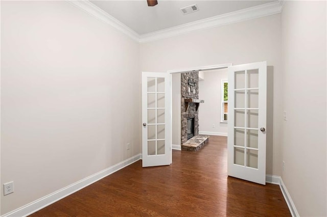 unfurnished room with french doors, dark hardwood / wood-style flooring, ornamental molding, ceiling fan, and a stone fireplace