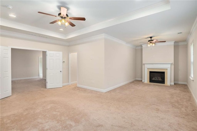 unfurnished living room featuring ceiling fan, light colored carpet, ornamental molding, and a tray ceiling