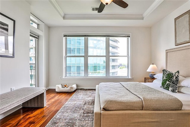 bedroom with hardwood / wood-style floors, ceiling fan, a raised ceiling, and ornamental molding