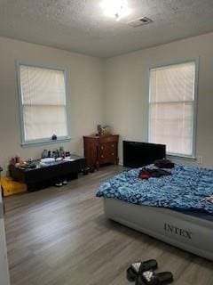 bedroom with light hardwood / wood-style floors and a textured ceiling