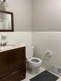 bathroom featuring vanity, tile walls, and toilet