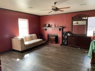 living room with a brick fireplace, dark hardwood / wood-style floors, and ceiling fan