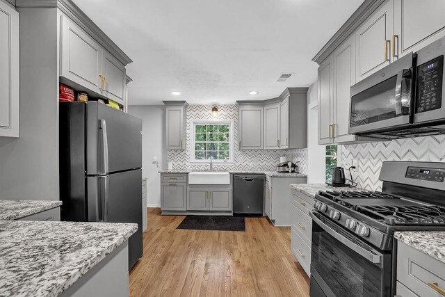 4066 Covered Bridge Rd SW, Smyrna, GA 30082 - kitchen with stainless steel appliances, gray cabinets, light wood-style floors, decorative backsplash, and recessed lighting