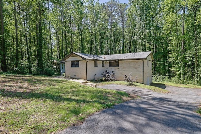 4066 Covered Bridge Rd SW, Smyrna, GA 30082 - view of front facade featuring a forest view, brick siding, driveway, and a front lawn