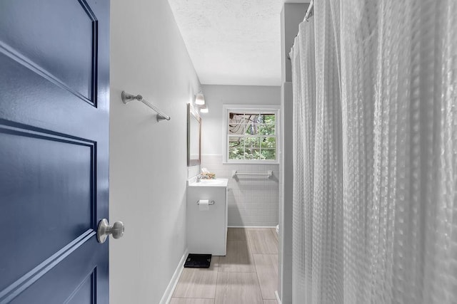 4066 Covered Bridge Rd SW, Smyrna, GA 30082 - bathroom with vanity, tile walls, a textured ceiling, a wainscoted wall, and a shower with curtain