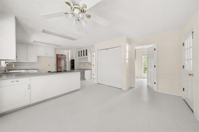 127 Roe Hampton Ln, Stone Mountain, GA 30087 - kitchen with black electric cooktop, ceiling fan, white cabinets, a peninsula, and decorative backsplash