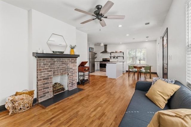 living area featuring recessed lighting, ceiling fan, a fireplace, and light wood-type flooring