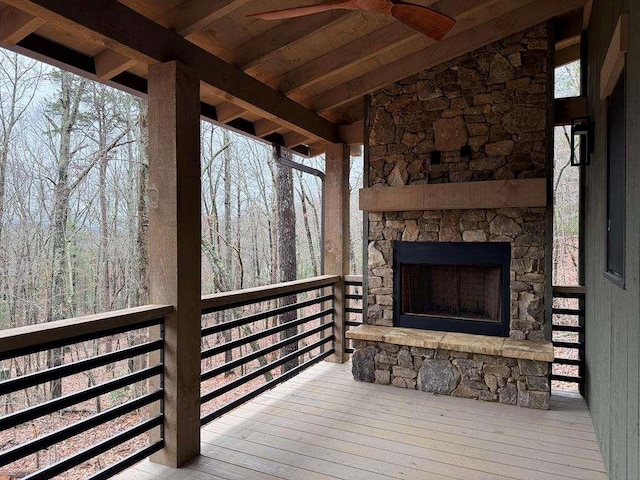 deck with ceiling fan and an outdoor stone fireplace