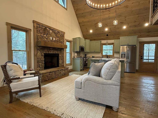 living room with a wealth of natural light, a stone fireplace, sink, and hardwood / wood-style floors