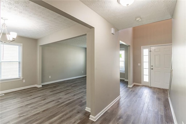 entryway featuring wood finished floors, a textured ceiling, and a notable chandelier
