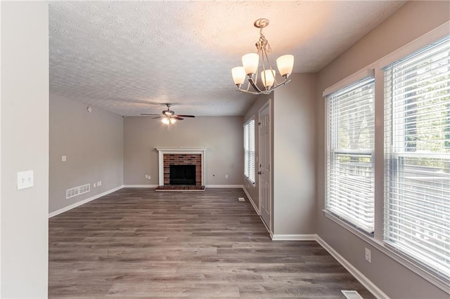 unfurnished living room featuring wood finished floors, visible vents, baseboards, a textured ceiling, and ceiling fan with notable chandelier