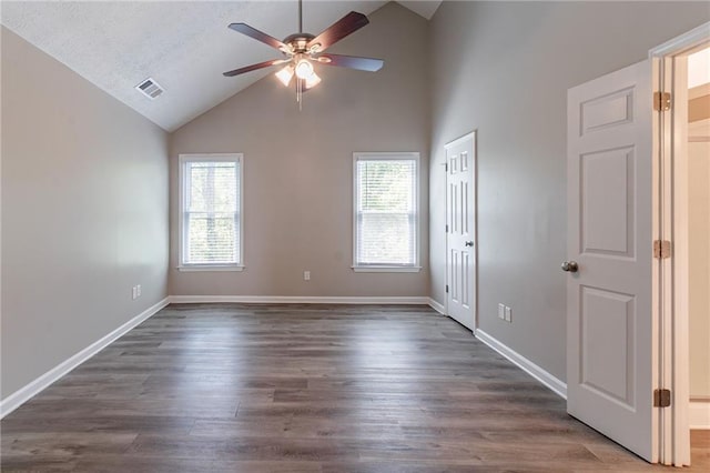 empty room featuring dark wood-type flooring, a wealth of natural light, ceiling fan, and visible vents