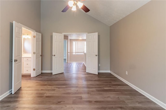 unfurnished bedroom with high vaulted ceiling, baseboards, and wood finished floors