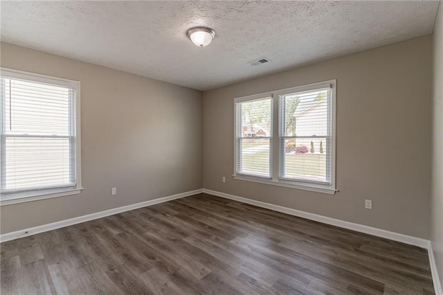 empty room with baseboards, dark wood-style flooring, and a textured ceiling