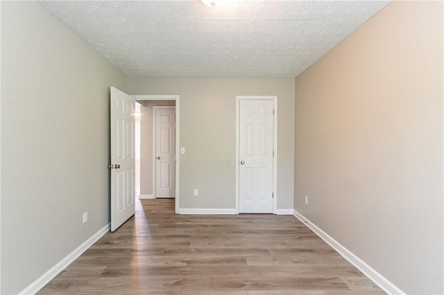 unfurnished bedroom with light wood finished floors, baseboards, and a textured ceiling