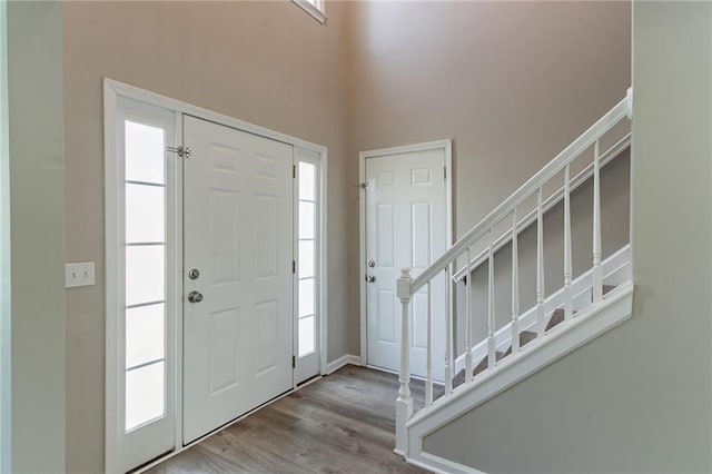foyer entrance featuring stairway, a high ceiling, and wood finished floors