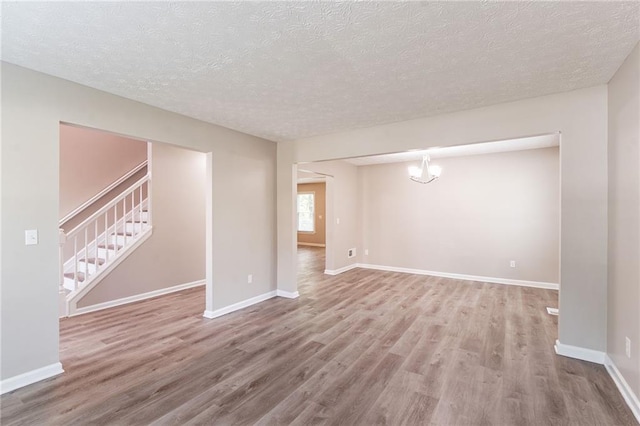 basement with wood finished floors, a textured ceiling, baseboards, and stairway