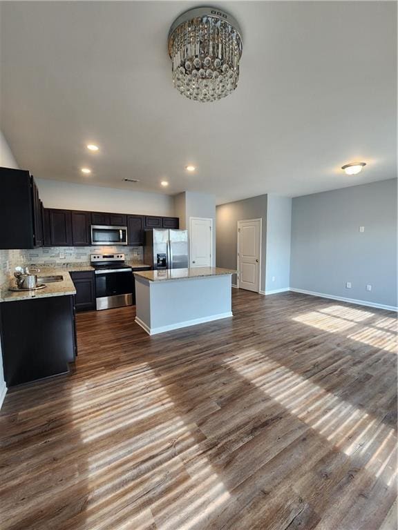 kitchen featuring a kitchen island, sink, backsplash, stainless steel appliances, and dark wood-type flooring