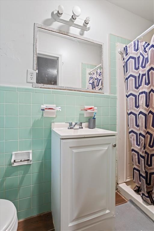 bathroom featuring tile walls, vanity, curtained shower, and toilet