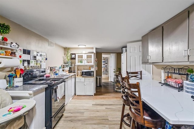 kitchen featuring light hardwood / wood-style floors, white cabinetry, and electric range