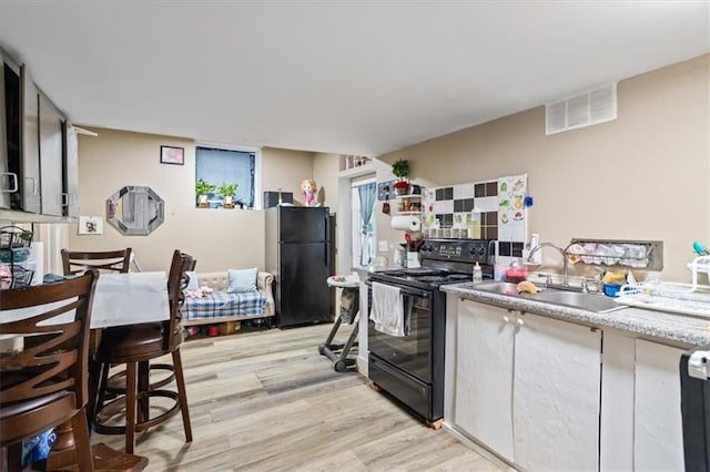 kitchen featuring light hardwood / wood-style flooring, black appliances, and sink