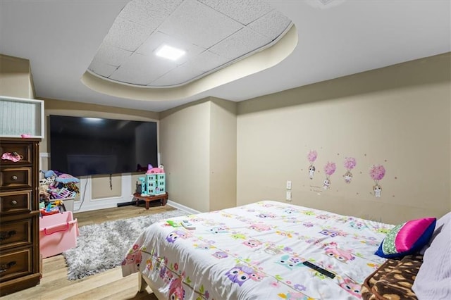 bedroom with hardwood / wood-style floors and a raised ceiling