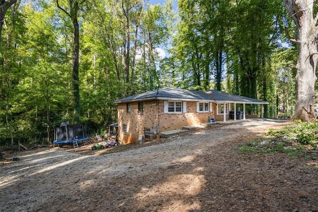 rear view of property featuring a trampoline and a patio