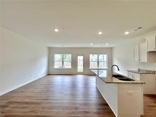 1958 Asher Ln Unit 50, Conyers, GA 30013 - kitchen with a sink, light stone counters, white cabinets, a center island with sink, and wood finished floors