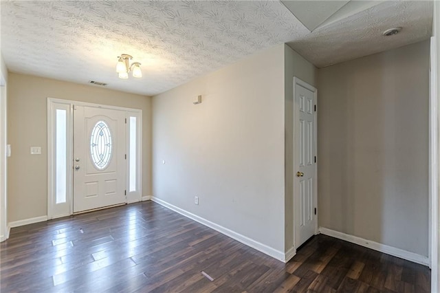 foyer entrance featuring dark wood-type flooring, a notable chandelier, and a textured ceiling