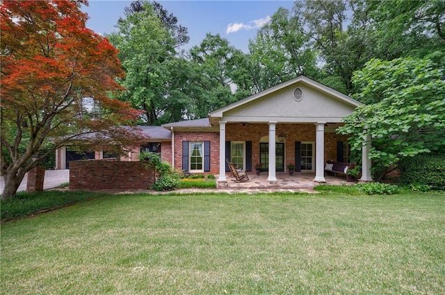 back of house with a lawn, brick siding, and a patio
