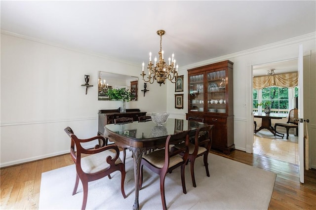 dining room featuring baseboards, ornamental molding, wood finished floors, and a notable chandelier