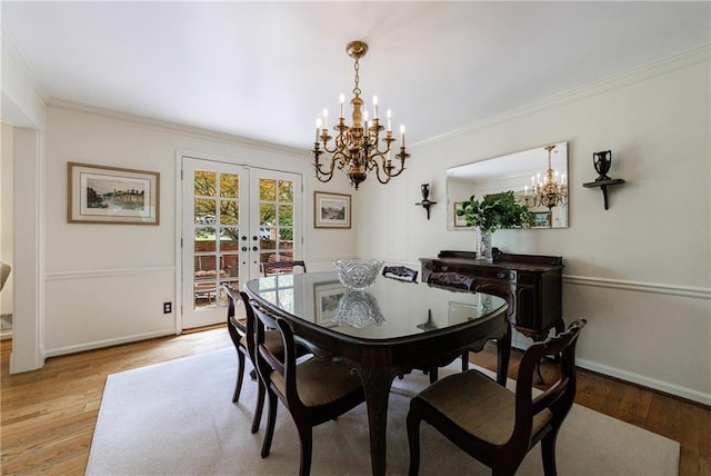 dining space with crown molding, light wood-style floors, french doors, and a chandelier