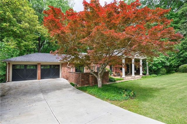 view of front of house with an attached garage, a front lawn, brick siding, and concrete driveway