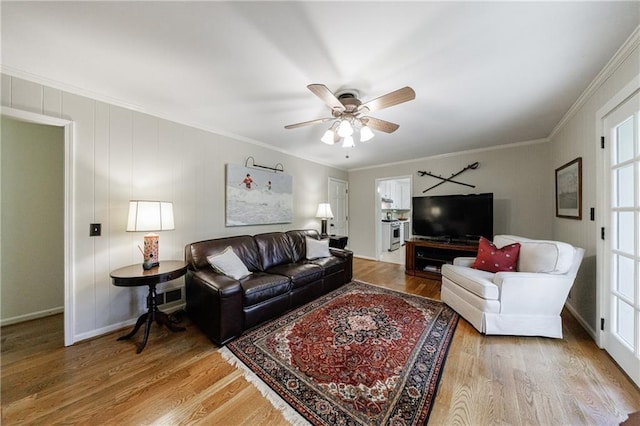 living room featuring baseboards, ornamental molding, ceiling fan, and wood finished floors