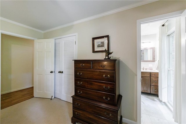 bedroom featuring crown molding, baseboards, ensuite bathroom, and a closet