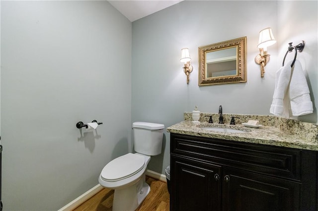 bathroom featuring toilet, baseboards, wood finished floors, and vanity