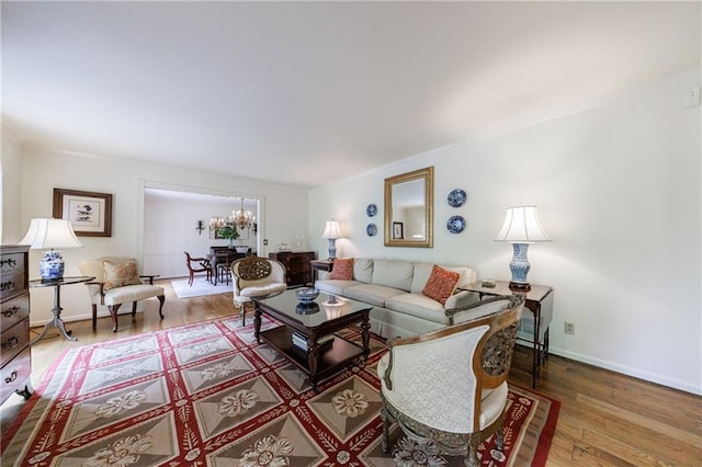 living room featuring baseboards, a notable chandelier, and wood finished floors